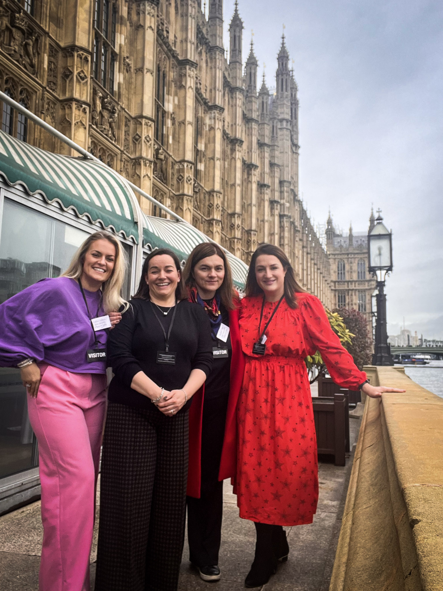 Four women posing standing on the terrace outside the Houses of Parliament. St Columba's House of Commons Lunch 2022