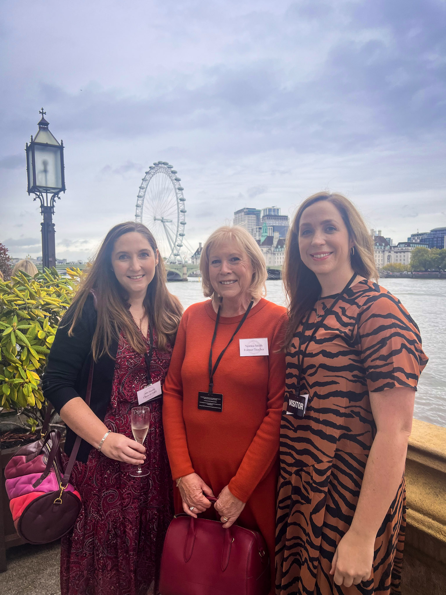 Three women are standing with the London Eye and the Thames in the background. St Columba's House of Commons Lunch 2022